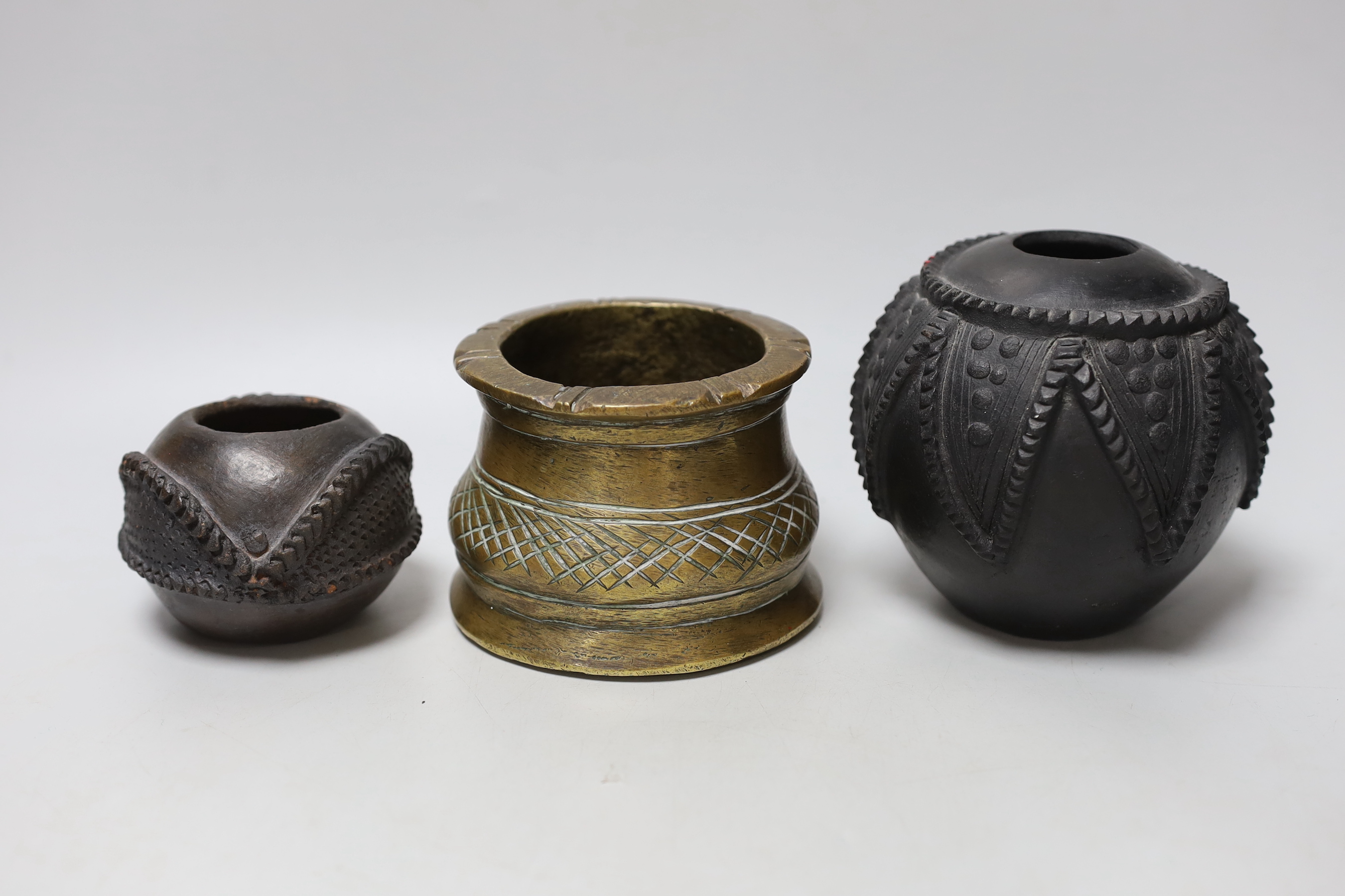 An African bronze mortar and two pots with carved and incised decoration, the largest 12cm high